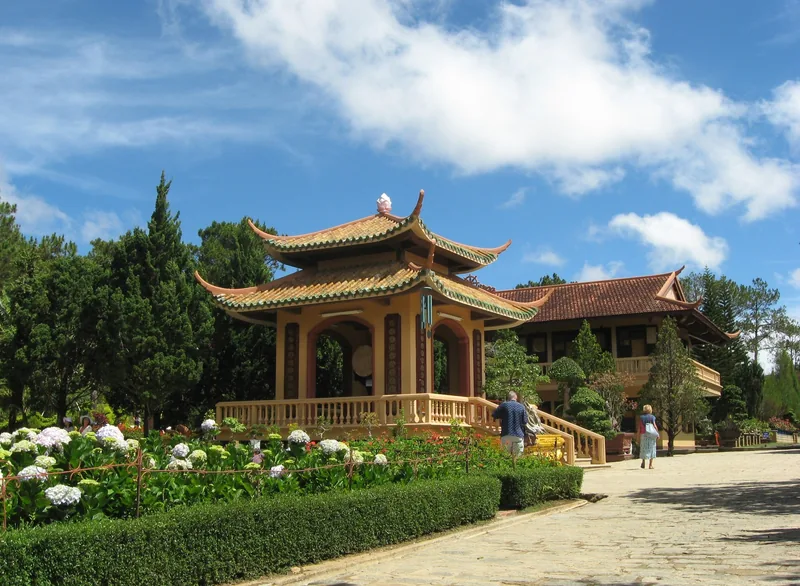 Nhà bát giác mái ngói và công trình chùa giữa những bụi hoa tại Thiền viện Trúc Lâm, Đà Lạt.