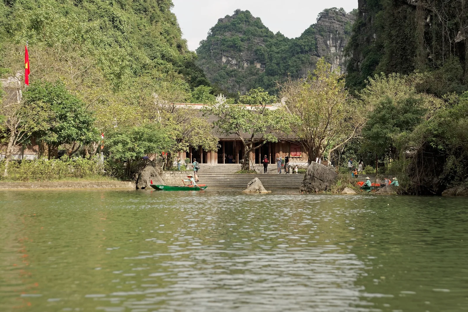 Ngôi đền ven sông cùng những chiếc thuyền nan nằm dưới chân núi đá vôi tại Tràng An, Ninh Bình.
